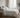 Fris opgemaakt bed met luchtig wit en zandkleurig beddengoed in een rustige Europese slaapkamer, zacht ochtendlicht en een koele, comfortabele sfeer.