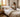 Neatly made bed with soft neutral bedding, certification tags in hand, and natural daylight in a calm European bedroom setting.