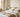 Neatly made bed with crisp white and beige bedding in a calm European bedroom, soft daylight highlighting smooth fabric and layered texture.