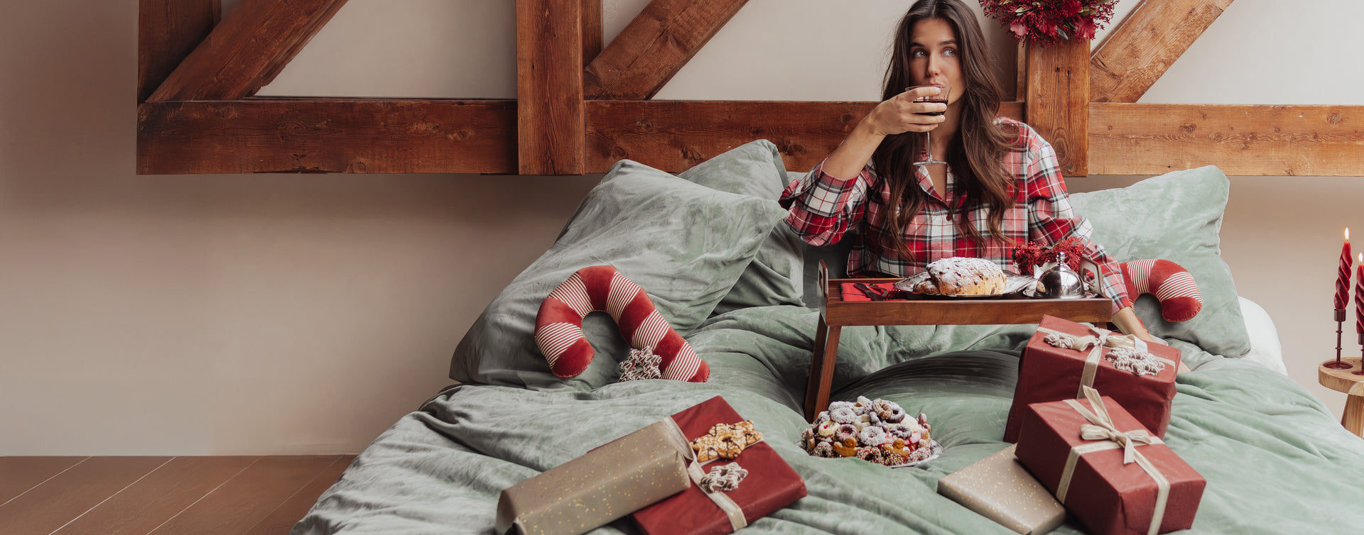 SJUMO Forest Green bedding, wrapped Christmas gifts and a woman relaxing on the bed.