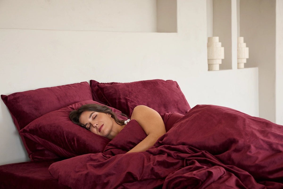 Woman sleeping on SJUMO Silky Smooth pillowcases under a matching duvet cover in Burgundy